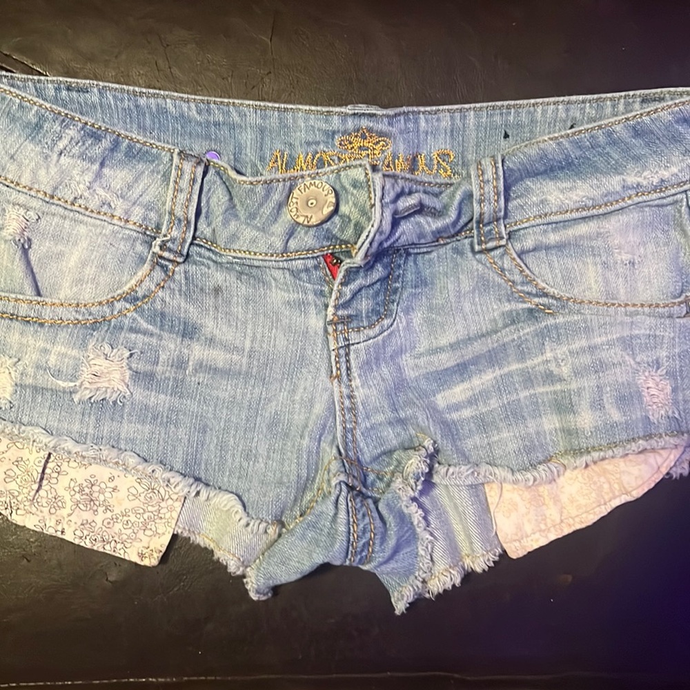 Almost famous low rise denim shorts with decorative pockets hanging out. Size 3